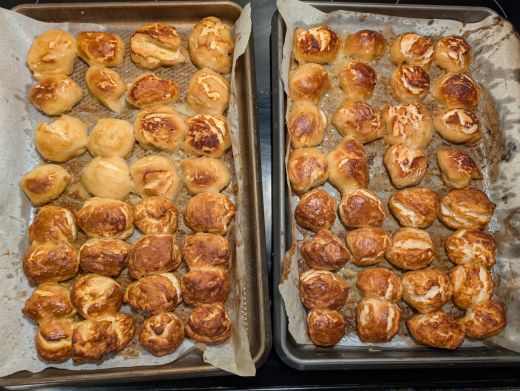 A photo of 64 pretzel bites made form pre-made biscuit dough across two trays (& parchment paper) & a few cooking methods.