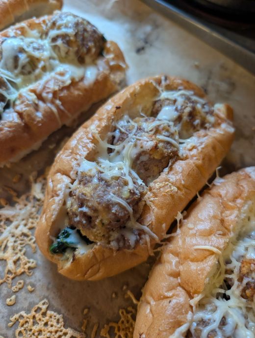 A hearty meatball sub inspired by Italian wedding soup, featuring tender meatballs, greens, and melted cheese on a toasted hoagie roll.