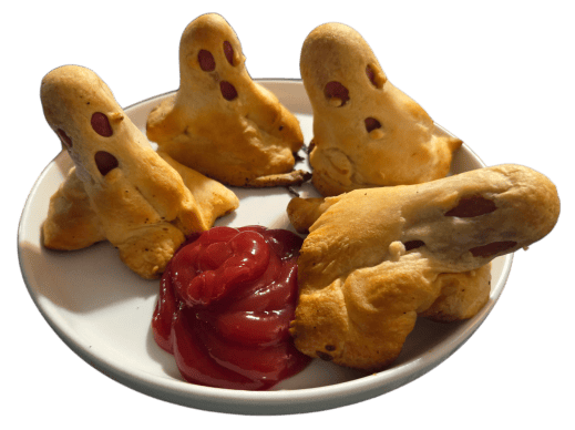 4 ghost styled hot dogs standing on a white plate with some ketchup.